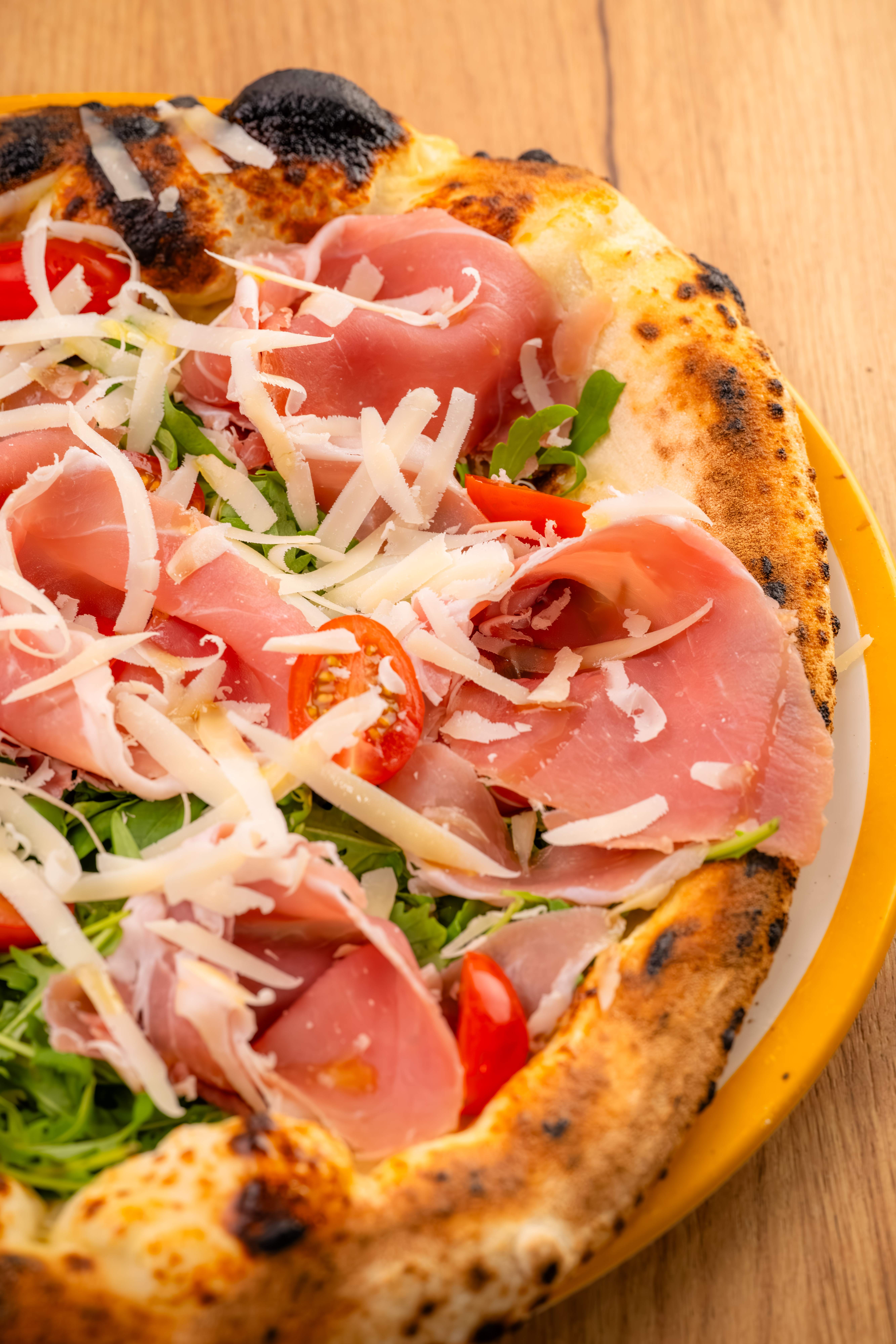 Pizza napolitaine au jambon de Parme, roquette, tomates cerises et grana